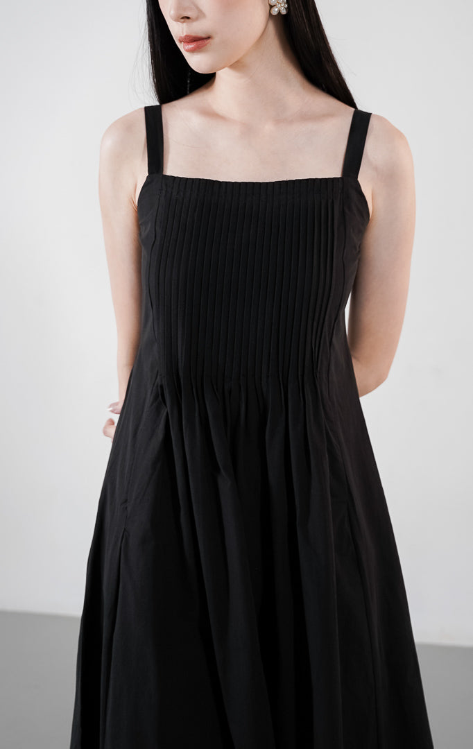Skylar Dress warna hitam, gaun A-line tanpa lengan dengan detail lipatan pintuck vertikal di bagian dada dan tali bahu yang bisa diatur.1