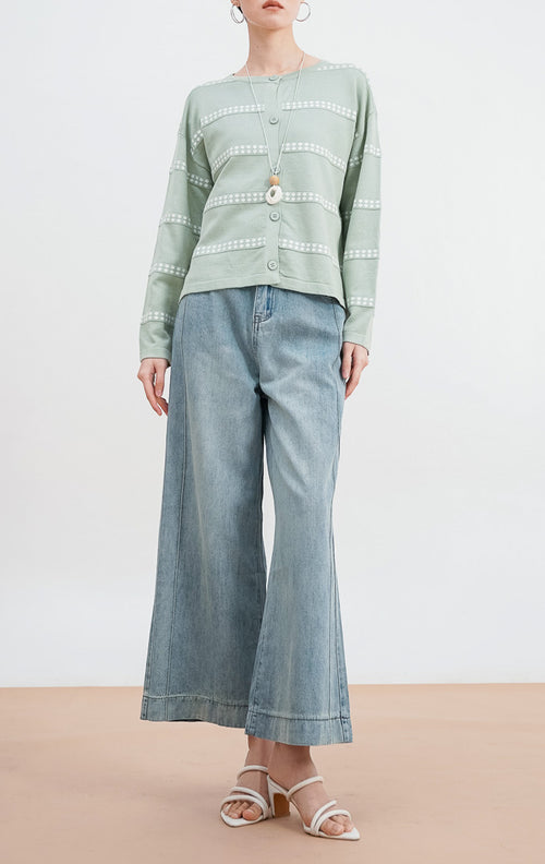 Model mengenakan Soleil Cardigan warna sage, kardigan rajut lengan panjang dengan motif garis horizontal titik-titik putih dan kancing depan senada