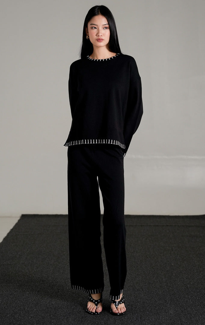 Soobin Knit Set warna hitam, yang terdiri dari atasan lengan panjang dan celana panjang rajut berpotongan longgar dengan detail jahitan pola putih di bagian ujung.