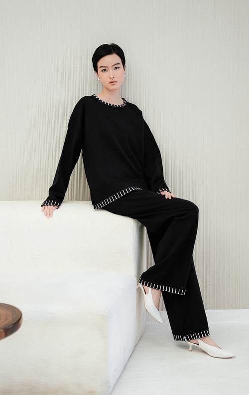 One set pakaian wanita Soobin Set warna hitam berbahan rajut (knit) halus, terdiri dari atasan lengan panjang dan celana panjang dengan aksen motif garis list putih di bagian hem/pinggiran. 