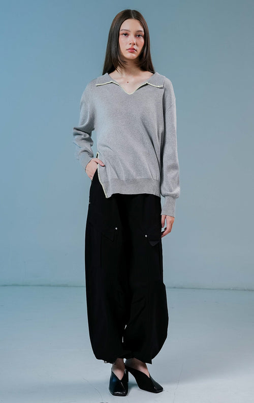 Model wanita mengenakan Maddox V-Neck Contrast Stitch Collared Sweater warna grey, baju sweater rajut wanita lengan panjang berwarna abu-abu dengan detail jahitan kontras putih di kerah.