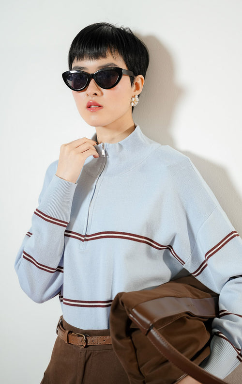 Model wanita mengenakan Jayce Half-Zip Striped Pullover Sweater warna blue, baju atasan sweater rajut wanita lengan panjang warna biru muda motif garis cokelat dengan kerah resleting half-z