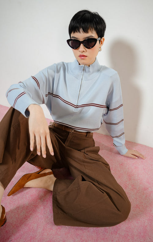 Model wanita mengenakan Jayce Half-Zip Striped Pullover Sweater warna blue, baju atasan sweater rajut wanita lengan panjang warna biru muda motif garis cokelat dengan kerah resleting half-zip