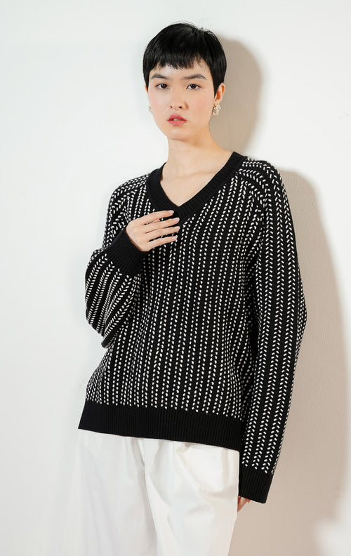 Model wanita mengenakan Brooke Sweater warna black, baju atasan sweater rajut wanita lengan panjang berwarna hitam dengan detail motif tekstur putih kontras yang modis. 
