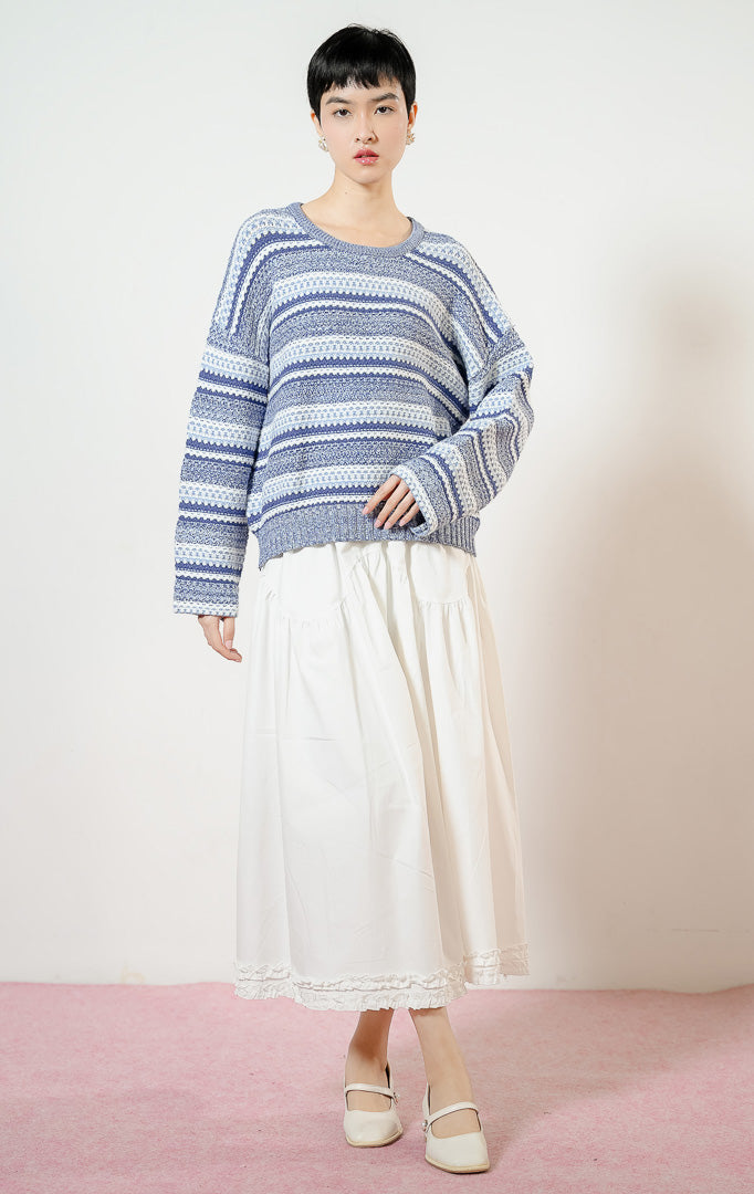 Model wanita mengenakan Winslow Multi-Patterned Jacquard Knit Sweater warna blue, baju sweater rajut longgar wanita lengan panjang motif etnik kombinasi warna gradasi biru dan putih.