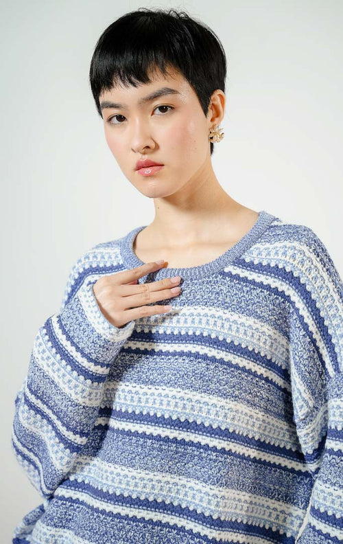 Model wanita mengenakan Winslow Multi-Patterned Jacquard Knit Sweater warna blue, baju sweater rajut longgar wanita lengan panjang motif etnik kombinasi warna gradasi biru dan putih.