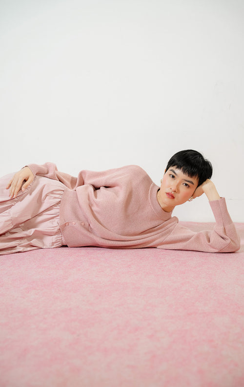 Detail dekat Cerise Button Hem Knit Sweater warna dusty pink, atasan sweater rajut wanita lengan panjang dengan karet pinggang rib lebar berdetail kancing.