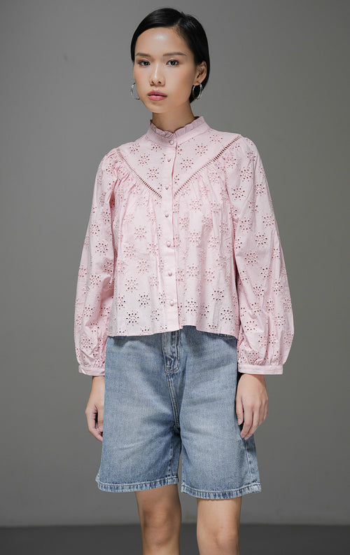 Atasan blouse wanita Sylvia Top warna pink bahan eyelet bordir dengan detail kerah frill rumbai dan kancing depan bungkus yang manis. 