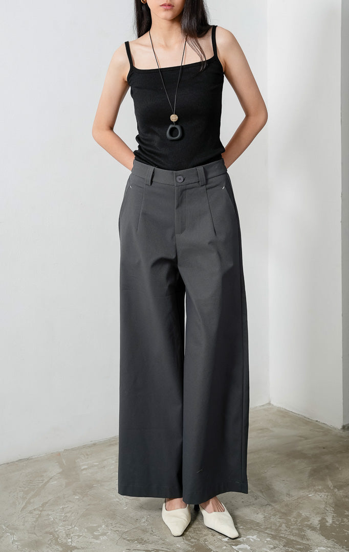 Celana panjang wanita siluet lurus (straight-leg trousers) warna abu-abu tua (dark grey) Sylvie Pants dengan ban pinggang terstruktur berloop ikat pinggang (belt loops), kancing depan, saku miring, dan karet elastis di bagian belakang pinggang (elasticated back waistband). 

