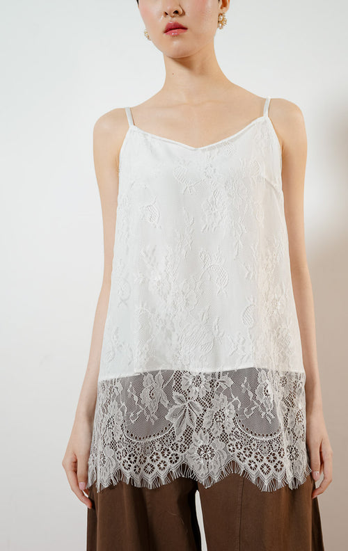 Model wanita mengenakan Juliet Lace Tank Top warna white, atasan camisole tank top satin wanita berwarna putih dengan detail kelim renda brokat bunga transparan yang anggun. 