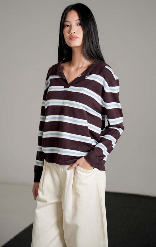 Tayden Sweater Dark Brown, atasan rajut cokelat tua motif garis biru dan putih dengan kerah polo, dipadukan dengan celana panjang broken white.