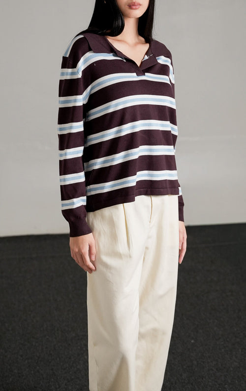 Tayden Sweater Dark Brown, atasan rajut cokelat tua motif garis biru dan putih dengan kerah polo, dipadukan dengan celana panjang broken white.