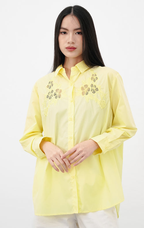Close-up model mengenakan Tessa Top warna yellow, kemeja katun lengan panjang dengan detail bordir bunga lace transparan warna kuning senada di bagian dada.
