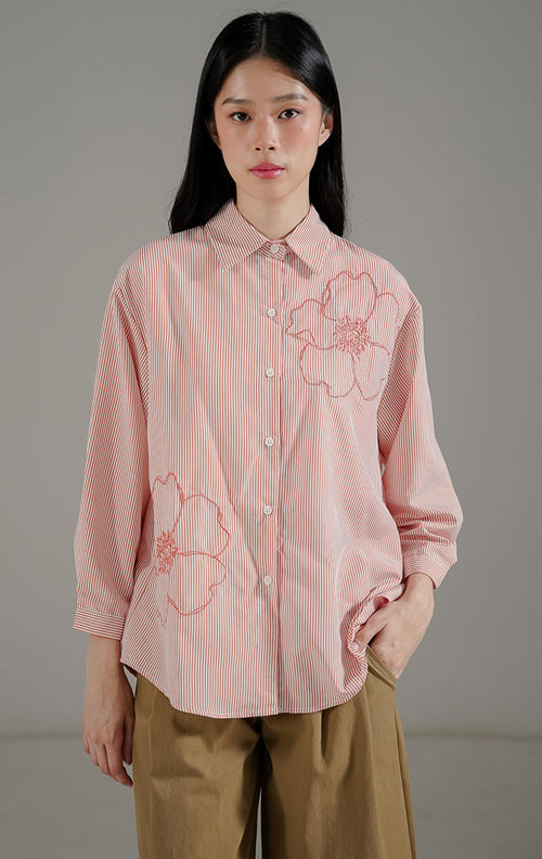 Amour Top Pink Peach dari This Is April, kemeja lengan panjang motif garis warna peach dengan detail bordir bunga besar dan potongan asimetris.