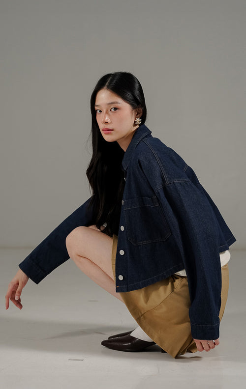 Jaket denim crop wanita Anakin Jacket Indigo warna biru gelap dari This Is April, dilengkapi kerah, kancing depan, dan dua saku di bagian dada.