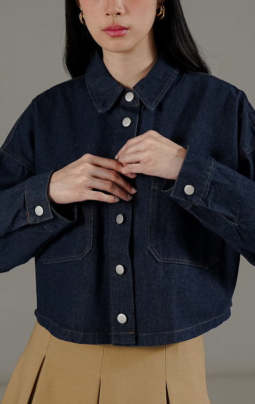 Jaket denim crop wanita Anakin Jacket Indigo warna biru gelap dari This Is April, dilengkapi kerah, kancing depan, dan dua saku di bagian dada.