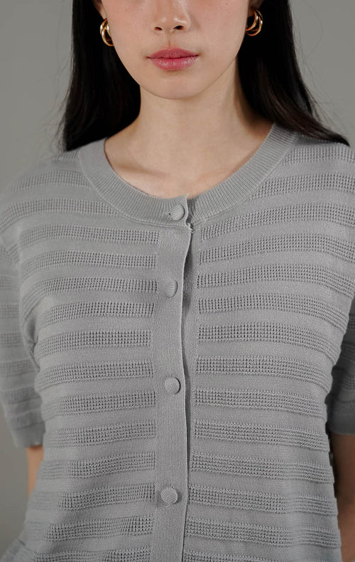Annalina Cardigan Grey dari This Is April, atasan rajut lengan pendek warna abu-abu dengan motif garis benang timbul dan kancing depan aktif.