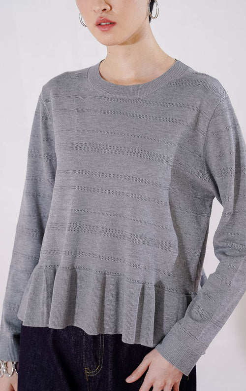 Sweater rajut wanita lengan panjang Arkiana Sweater dari This Is April berwarna abu-abu dengan motif garis berlubang (perforated) horizontal dan detail potongan kerut (ruffle/peplum) di bagian bawah 