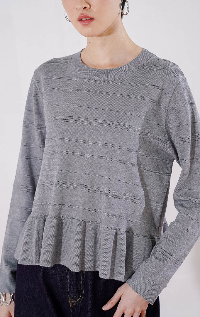 Sweater rajut wanita lengan panjang Arkiana Sweater dari This Is April berwarna abu-abu dengan motif garis berlubang (perforated) horizontal dan detail potongan kerut (ruffle/peplum) di bagian bawah 
