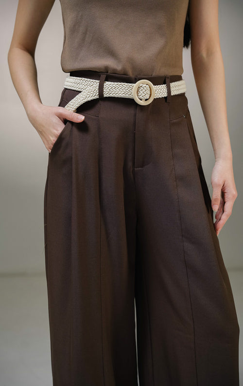 Celana panjang wanita This Is April Arthou Pants warna cokelat tua (dark brown), model celana kain highwaist dengan kancing depan, tempat ikat pinggang, saku samping fungsional, dan karet elastis di bagian belakang. 