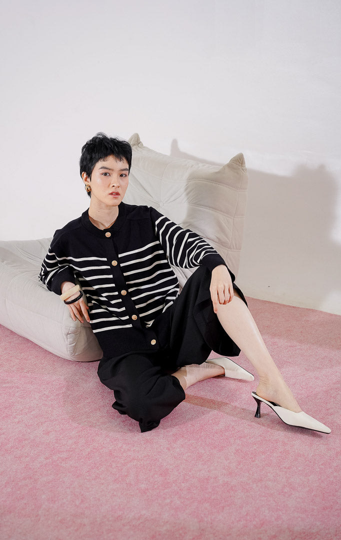 Tampak depan This Is April Aurelie Cardigan warna hitam, cardigan lengan panjang dengan motif garis putih horizontal, kerah bulat, dan detail kancing depan berwarna emas.