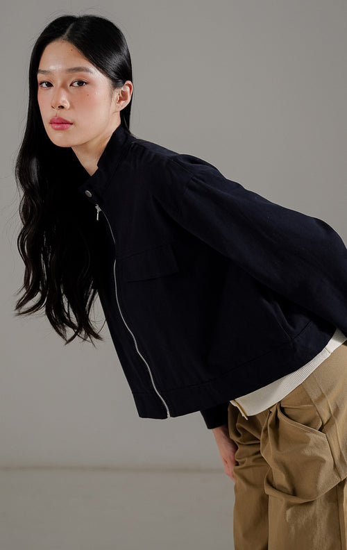 Averie Jacket Navy dari This Is April, jaket lengan panjang wanita warna biru navy dengan resleting depan, kerah tinggi (high-neck), dan detail saku dada.
