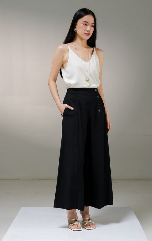 Celana panjang kulot wanita This Is April Blakeley Pants warna hitam pekat, model high-waist dengan detail tiga deret kancing hidup asimetris di bagian pinggang sisi kiri depan. 