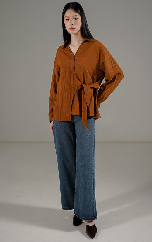 Bryanna Top Dark Brown dari This Is April, blus lengan panjang wanita warna cokelat tua dengan kerah V-neck dan detail tali pengikat di pinggang.