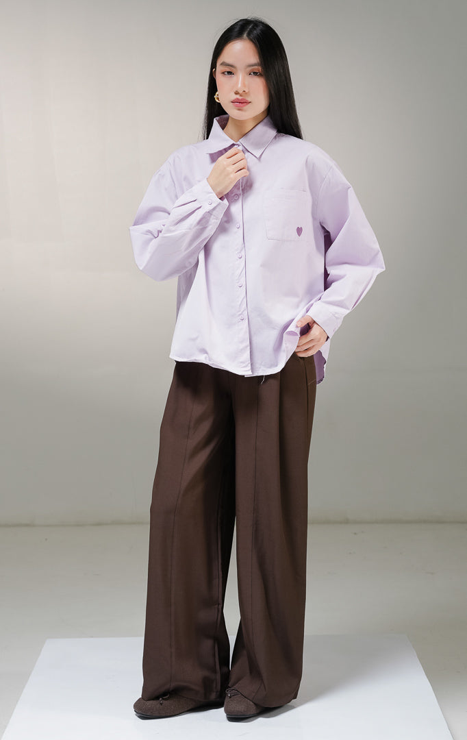 Kemeja basic lengan panjang wanita This Is April Claudette Top warna ungu muda (light purple), dilengkapi satu saku di dada kiri dengan detail bordiran bentuk hati kecil warna ungu tua.