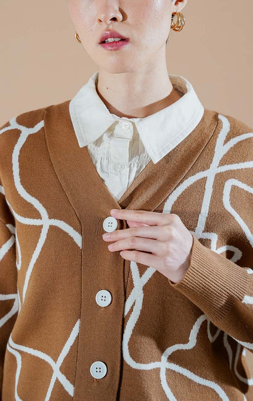 Coralina Cardigan Brown dari This Is April, cardigan rajut V-neck warna cokelat dengan motif garis abstrak putih dan kancing depan.