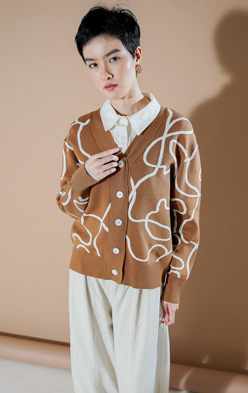 Coralina Cardigan Brown dari This Is April, cardigan rajut V-neck warna cokelat dengan motif garis abstrak putih dan kancing depan.