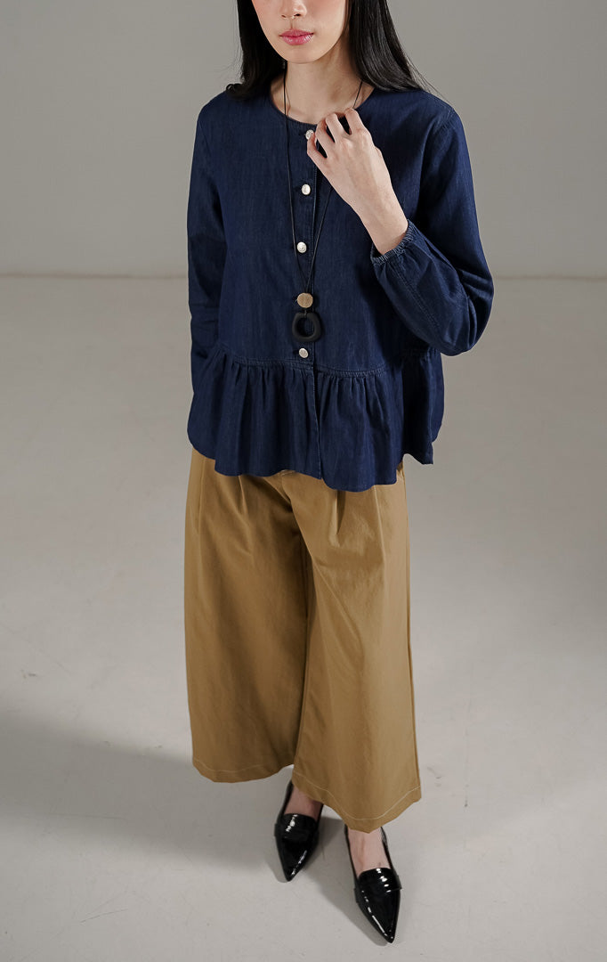 Deliana Top Indigo dari This Is April, blouse denim wanita lengan panjang warna indigo dengan detail kancing perak dan ruffle di bagian bawah.