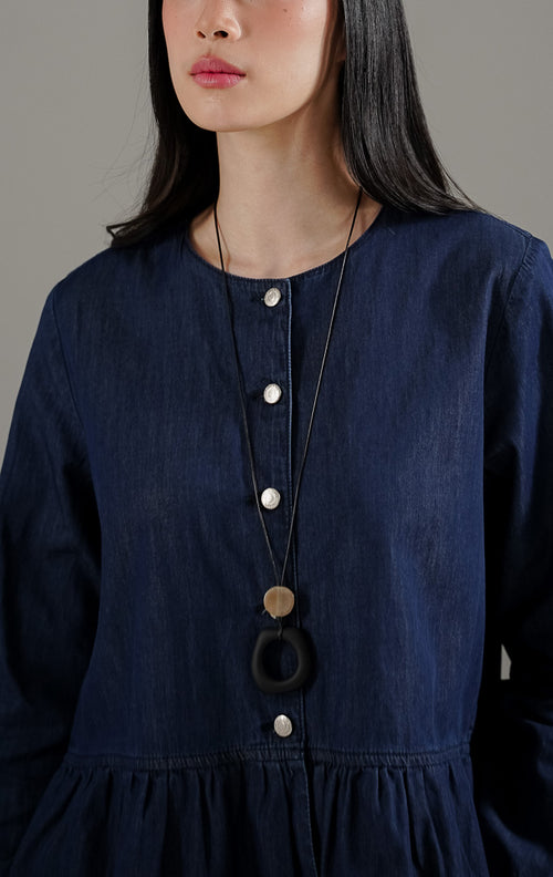 Deliana Top Indigo dari This Is April, blouse denim wanita lengan panjang warna indigo dengan detail kancing perak dan ruffle di bagian bawah.