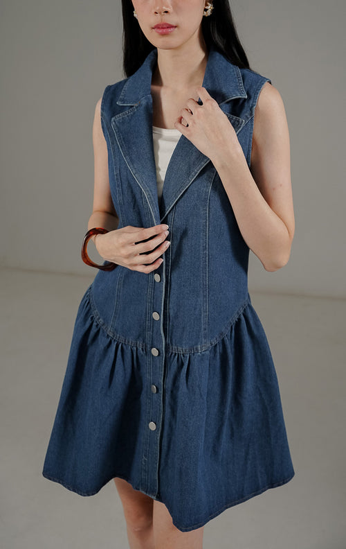 Eliette Dress Denim dari This Is April, gaun tanpa lengan kerah V dengan kancing depan dan siluet A-line warna biru denim.