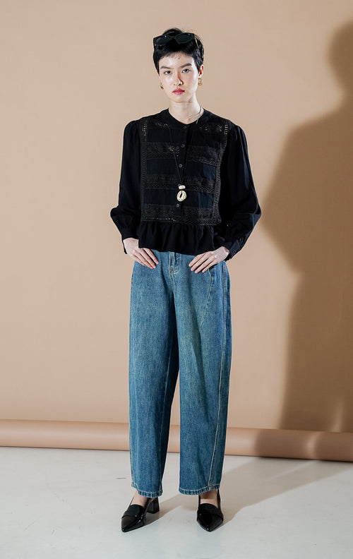 Eliot Top Black dari This Is April, blus katun lengan panjang warna hitam dengan detail panel bordir di dada dan aksen ruffle di bagian bawah (hem).