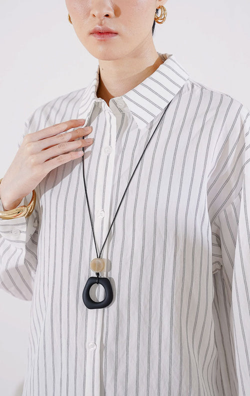 Atasan kemeja lengan panjang wanita This Is April Elysia Top warna putih dengan motif garis vertikal tipis (pin stripes) dan bahan katun. 
