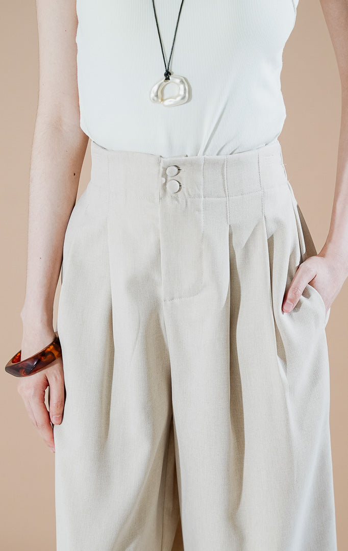 Endellion Pants Beige dari This Is April, celana panjang tailored wanita warna krem dengan detail dua kancing di pinggang, lipit depan (pleated), dan bahan katun terstruktur.