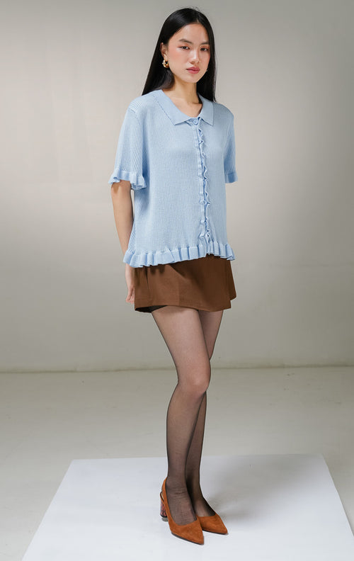 Atasan baju rajut lengan pendek wanita This Is April Eudora Top warna biru muda, model ribbed knit polo shirt berkerah dengan detail aksen kerut ruffle bergelombang di sepanjang kancing depan, ujung lengan, dan ujung bawah baju. 