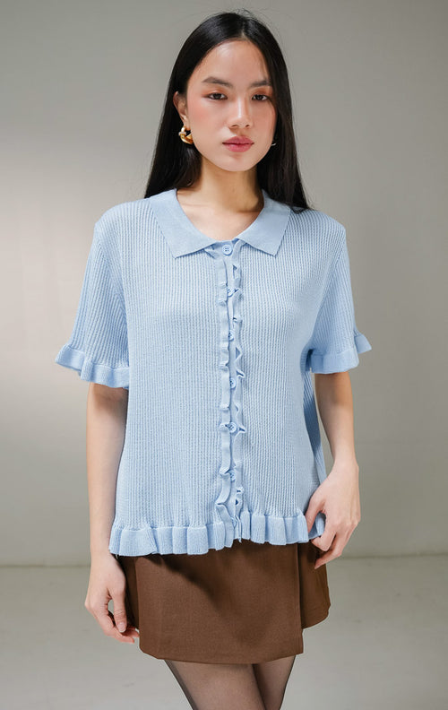 Atasan baju rajut lengan pendek wanita This Is April Eudora Top warna biru muda, model ribbed knit polo shirt berkerah dengan detail aksen kerut ruffle bergelombang di sepanjang kancing depan, ujung lengan, dan ujung bawah baju. 