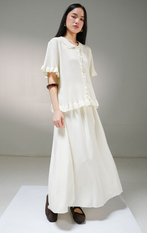 Atasan baju rajut lengan pendek wanita This Is April Eudora Top warna ivory (krem), model ribbed knit polo shirt berkerah dengan detail aksen kerut ruffle bergelombang di sepanjang kancing depan, ujung lengan, dan ujung bawah baju. 