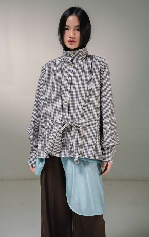 Kemeja lengan panjang wanita This Is April Francesca Top warna cokelat motif kotak-kotak kecil gingham, dilengkapi kancing depan dan detail tali serut aktif yang diikat simpul pita di bagian pinggang. 