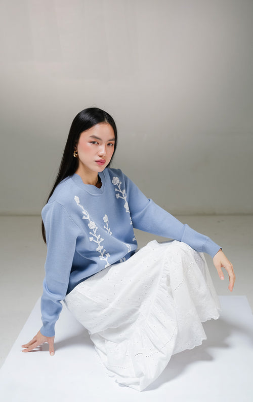 Atasan sweater rajut lengan panjang wanita This Is April Galina Sweater warna biru muda dengan detail tiga lajur motif bordir bunga timbul warna putih di bagian depan. 