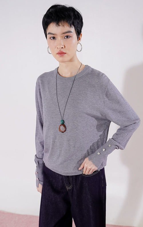 Sweater rajut wanita lengan panjang Gamora Sweater dari This Is April berwarna abu-abu (grey) berdesain minimalis polos dengan kerah bulat (crewneck) dan detail kancing perak elegan di bagian ujung lengan 