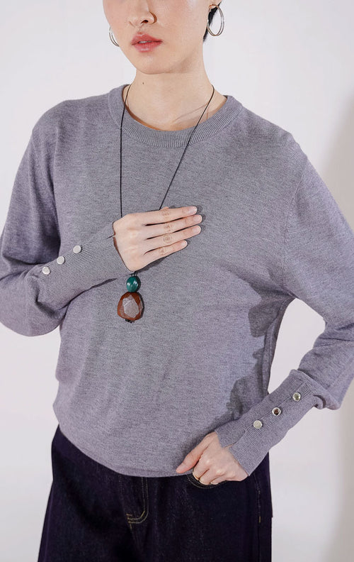 Sweater rajut wanita lengan panjang Gamora Sweater dari This Is April berwarna abu-abu (grey) berdesain minimalis polos dengan kerah bulat (crewneck) dan detail kancing perak elegan di bagian ujung lengan 