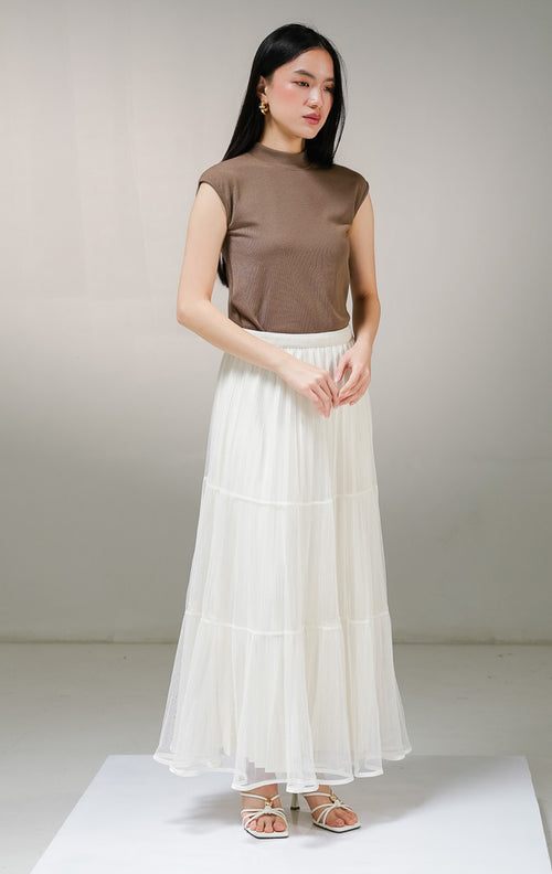 Rok panjang wanita This Is April Gianella Skirt warna ivory (krem), model tiered maxi skirt dengan lapisan luar kain tile tulle transparan bertingkat dan furing dalam bertekstur plisket. 