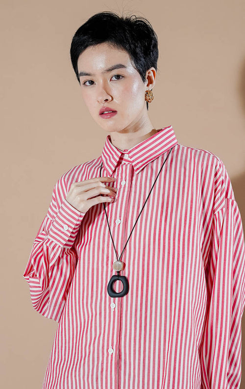 kemeja salur lengan panjang warna merah putih (Hippie Top Red) dari This Is April, dipadukan dengan aksesoris kalung hitam panjang.