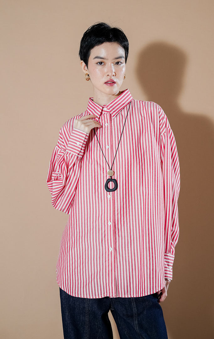 kemeja salur lengan panjang warna merah putih (Hippie Top Red) dari This Is April, dipadukan dengan aksesoris kalung hitam panjang.
