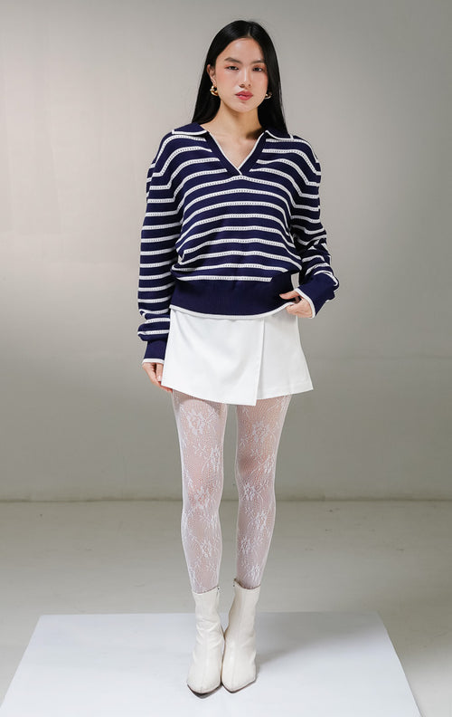 Atasan sweater rajut lengan panjang wanita This Is April Laurel Sweater warna navy motif garis horisontal putih, model kerah v-neck lebar dengan detail rajutan jaring berlubang kecil pada bagian stripe putih.