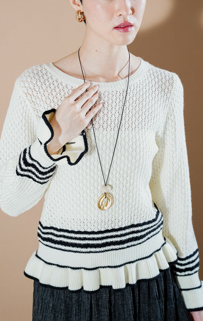 This Is April Laurent Cardigan Ivory, atasan rajut warna putih gading dengan detail ruffle dan aksen garis hitam di lengan dan ujung bawah.