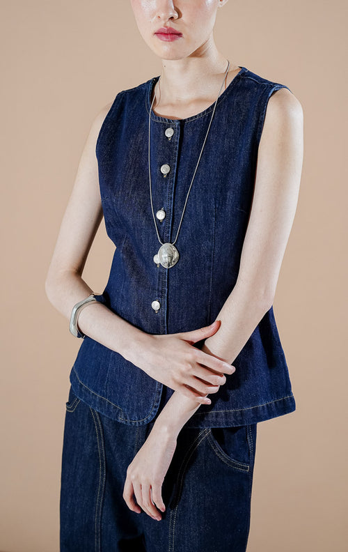 Lilou Vest Dark Denim dari This Is April, rompi waistcoat denim wanita warna biru gelap dengan deretan kancing perak di bagian depan dan siluet ramping terstruktur.